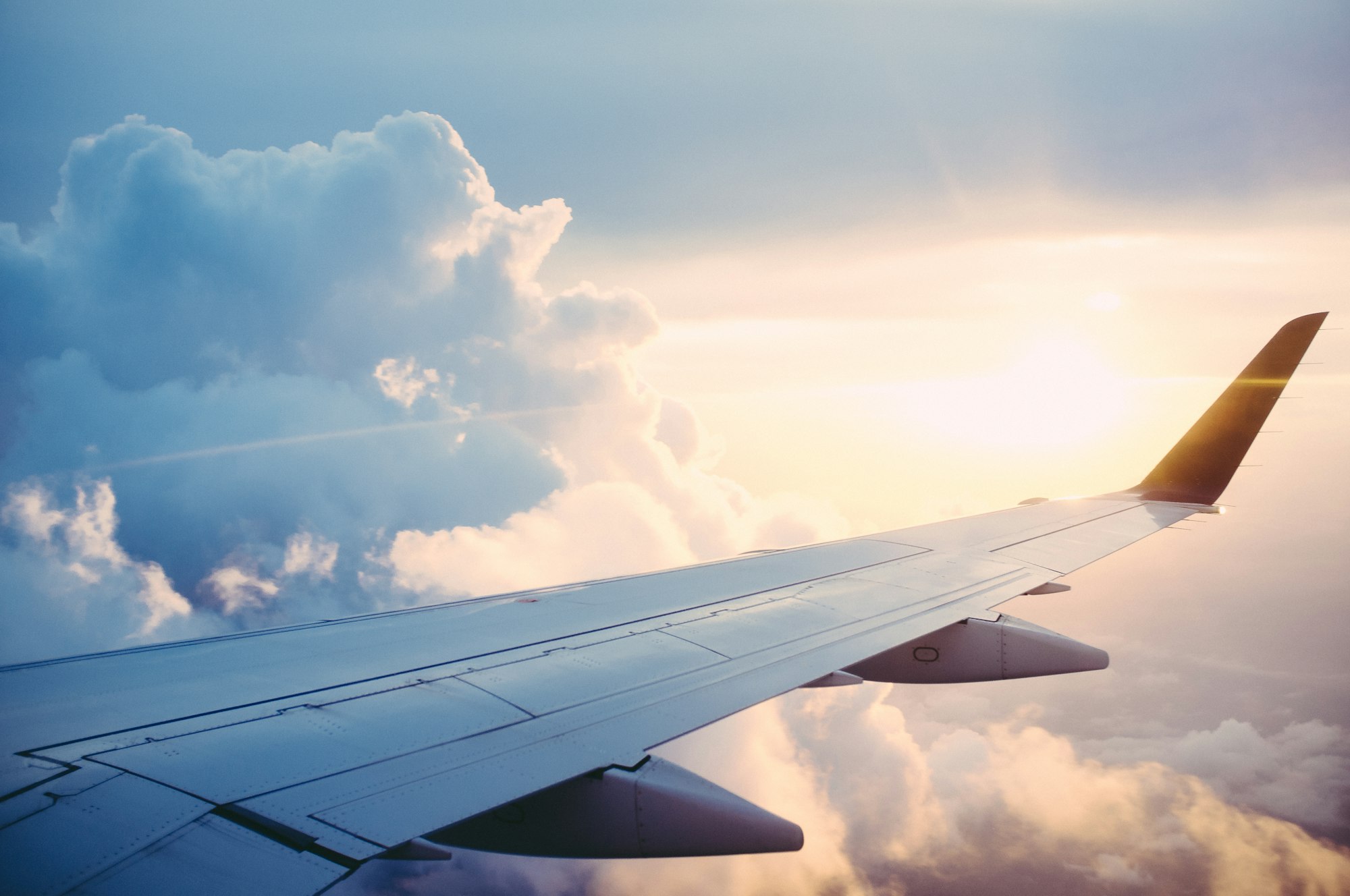 Aircraft wing above clouds at sunset, view from the cabin window